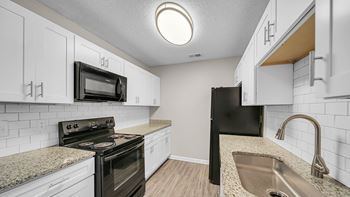 A kitchen with black appliances and white cabinets.
